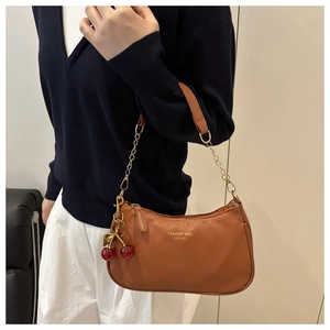 Detail of tan lychee pattern shoulder bag with gold chain and cherry pendant