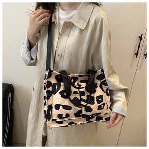 Detail of cow print crossbody bag with dual front pockets and black shoulder strap
