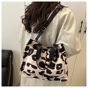 Leopard print crossbody bag with black wide straps shown from a side back view on model