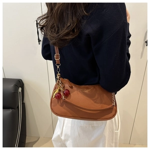 Detailed shot of brown crescent underarm bag with lychee grain texture and cherry charm