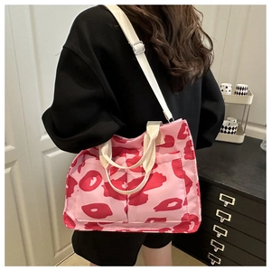 Detail of pink canvas tote bag with red print showing side view on a model