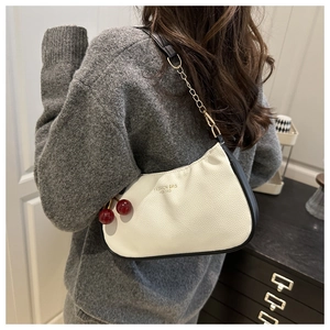 Detailed side view of white lychee texture shoulder bag with red cherry charm