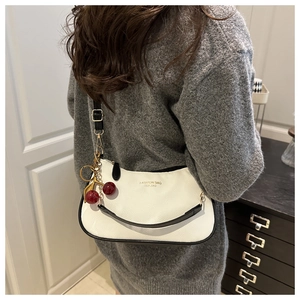 Close-up of a white lychee grain leather hobo bag with a red cherry charm detail