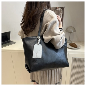 Close-up of soft black lychee textured tote bag with a contrasting white leather tag