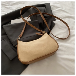 Detail of beige litchi pattern leather bag with brown trim on grey blazer
