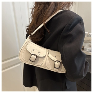 Detail of cream leather shoulder bag with utility pockets and black metal buckles