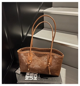 Detail of vintage brown tote bag showing textured leather material and knotted strap design