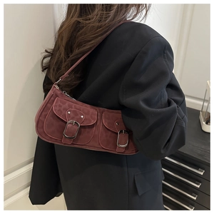 Detailansicht der dunkelroten Wildleder-Baguette-Tasche mit Metallschnallen am Model