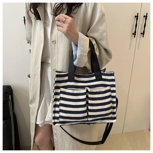 Detail of blue striped canvas tote showing front pockets and adjustable black strap