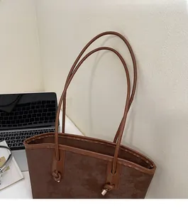 Detail of vintage brown tote bag featuring knotted straps and golden metal cap accents