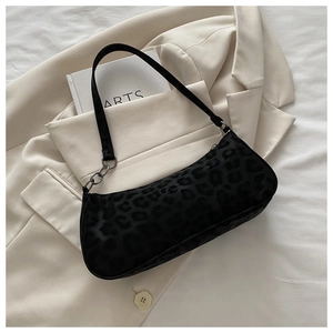 Detailansicht der schwarzen Baguette-Tasche mit Leopardenmuster auf einem beigen Blazer