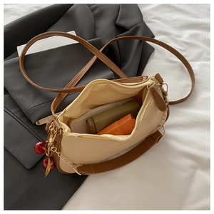 Detail of cream leather bag showing the cherry charm and interior storage capacity