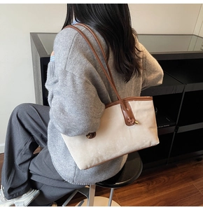 Close-up of beige tote bag with brown leather knotted strap and elegant metal details