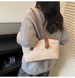 Detail of minimalist cream canvas tote bag with brown leather trim and knotted handles