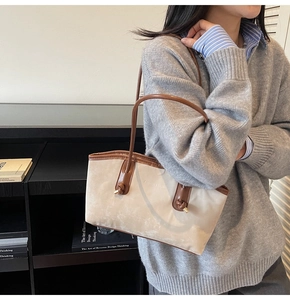 Detail view of beige tote bag with brown leather straps worn over the shoulder