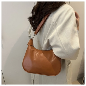 Brown faux leather hobo bag shown on model shoulder with minimalist beige coat