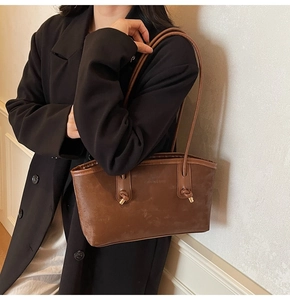 Macro detail of brown suede tote bag showing embossed FASHION & BAGS logo and texture