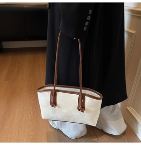 Detail view of white marble textured underarm bag with brown leather straps and lettering