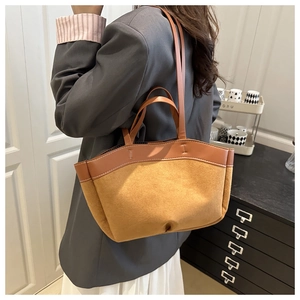 Braune Patchwork-Tragetasche aus Wildleder mit Doppelgriffen an einem Model im Business-Stil
