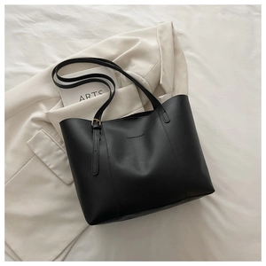 Close-up of black tote bag with embossed fashion text and golden metal buckle details