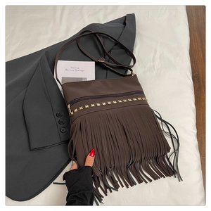 Détail du sac bandoulière en cuir marron avec clous dorés et longues franges bohèmes