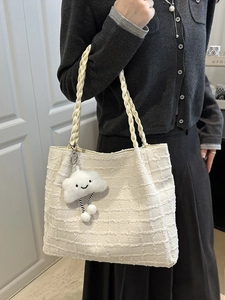White tweed tote bag with woven handles and a plush cloud charm shown on a model