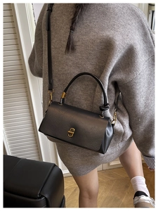 Detail of a black leather crossbody bag featuring a vintage gold rectangular twist lock