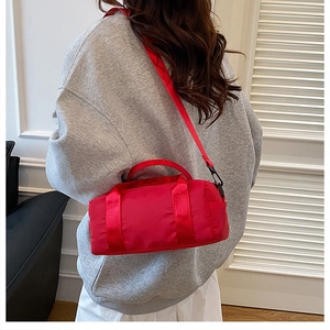 Detail showing red nylon crossbody bag worn over the shoulder on grey sweatshirt