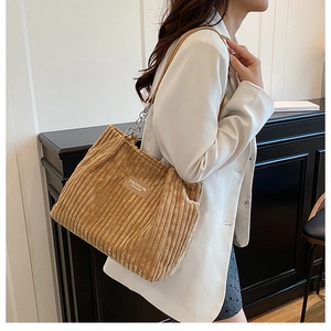 Close-up of corduroy tote bag featuring vertical texture and a metallic chain strap