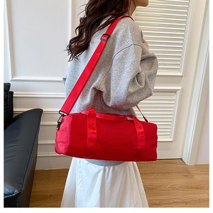 Dettaglio di una grande borsa sportiva rossa in nylon con tracolla rimovibile e manici