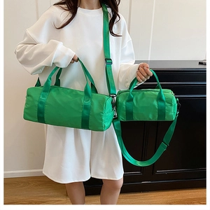 Model showcasing large and small green nylon cylinder bags for gym or travel use