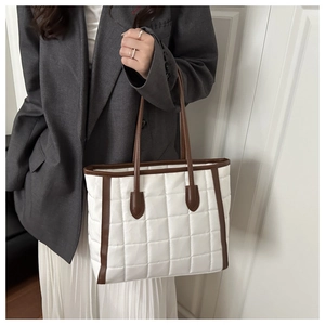 Detail of quilted white nylon tote with brown leather handles worn with a grey blazer