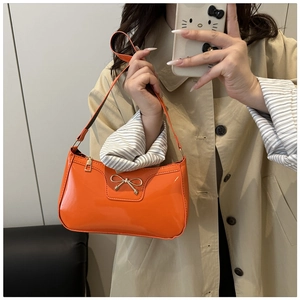 Détail du sac porté épaule en cuir verni orange vif avec boucle nœud en métal doré