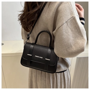 Close-up of black textured leather handbag with silver accents worn by a model