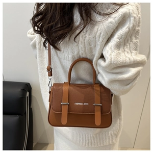 Sac bandoulière marron en similicuir grainé avec bandoulière réglable sur un pull blanc