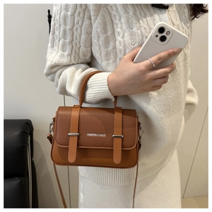 Detail of a brown leather crossbody bag with textured pebble finish and fashion logo