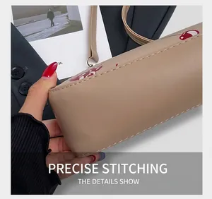 Close-up of beige PU leather square bag with red cherry prints and white precision stitching