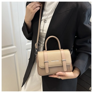 Détail du sac beige en cuir grainé avec boucle en métal porté par un mannequin