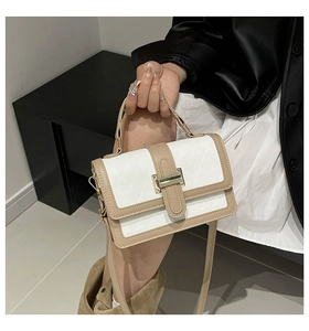 Detail of color-block quilted handbag with gold hardware lock and top handle