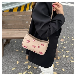 Detail of cherry print tote with gold hardware shown on a park bench background