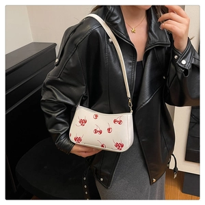 Close-up of white PU leather bag featuring red cherry print and golden metal buckles