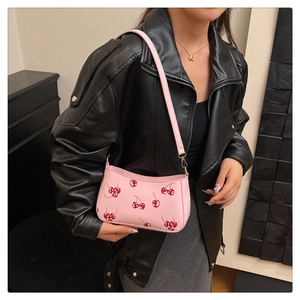 Gros plan du sac rose avec imprimé cerises et détails dorés sur veste en cuir noir
