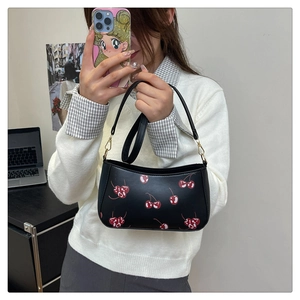 Close-up of black cherry print shoulder bag with gold metal hardware and PU leather texture