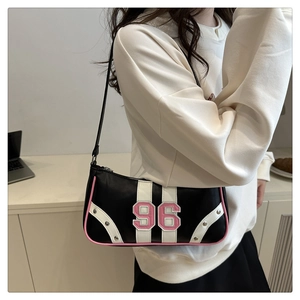 Close-up of retro black shoulder bag featuring pink number 96 embroidery and metal rivets