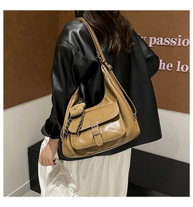 Detail of vintage brown PU leather hobo bag with front flap pocket and cute bear charm