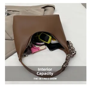 Internal capacity of dark brown shoulder bag showing sunglasses, phone and card holder