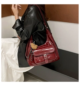 Deep red vintage hobo bag featuring contrast stitching and a plush bear pendant