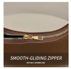 Detail showing high-quality gold metal zipper and smooth brown leather texture on a handbag