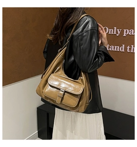Detail of mocha brown patent leather hobo bag featuring front pocket with silver buckle