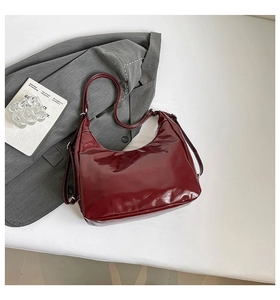 Detail of burgundy leather hobo bag with white stitching and adjustable strap